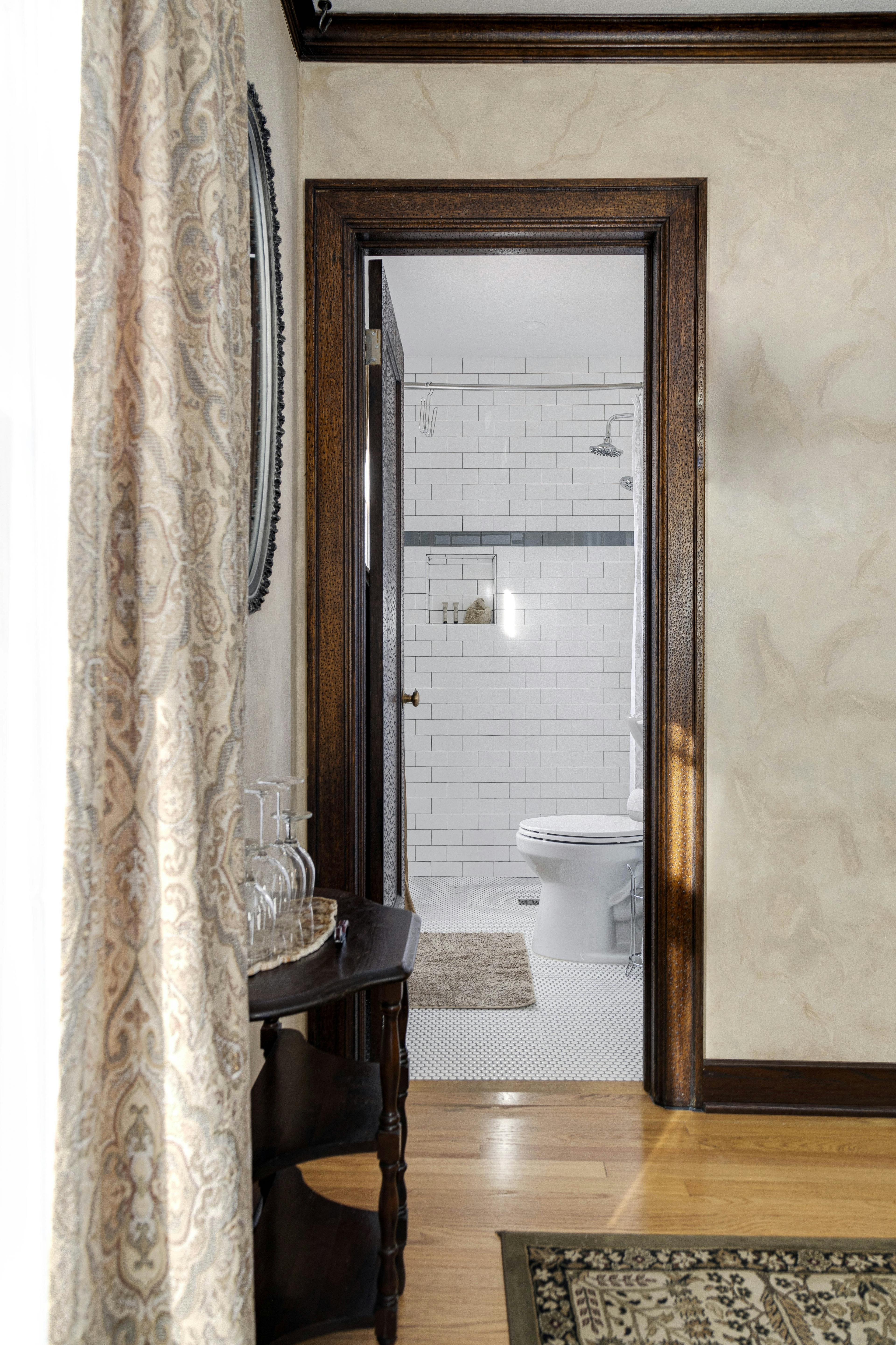 A view into a white-tiled bathroom from the guest room, with a shower and toilet visible.