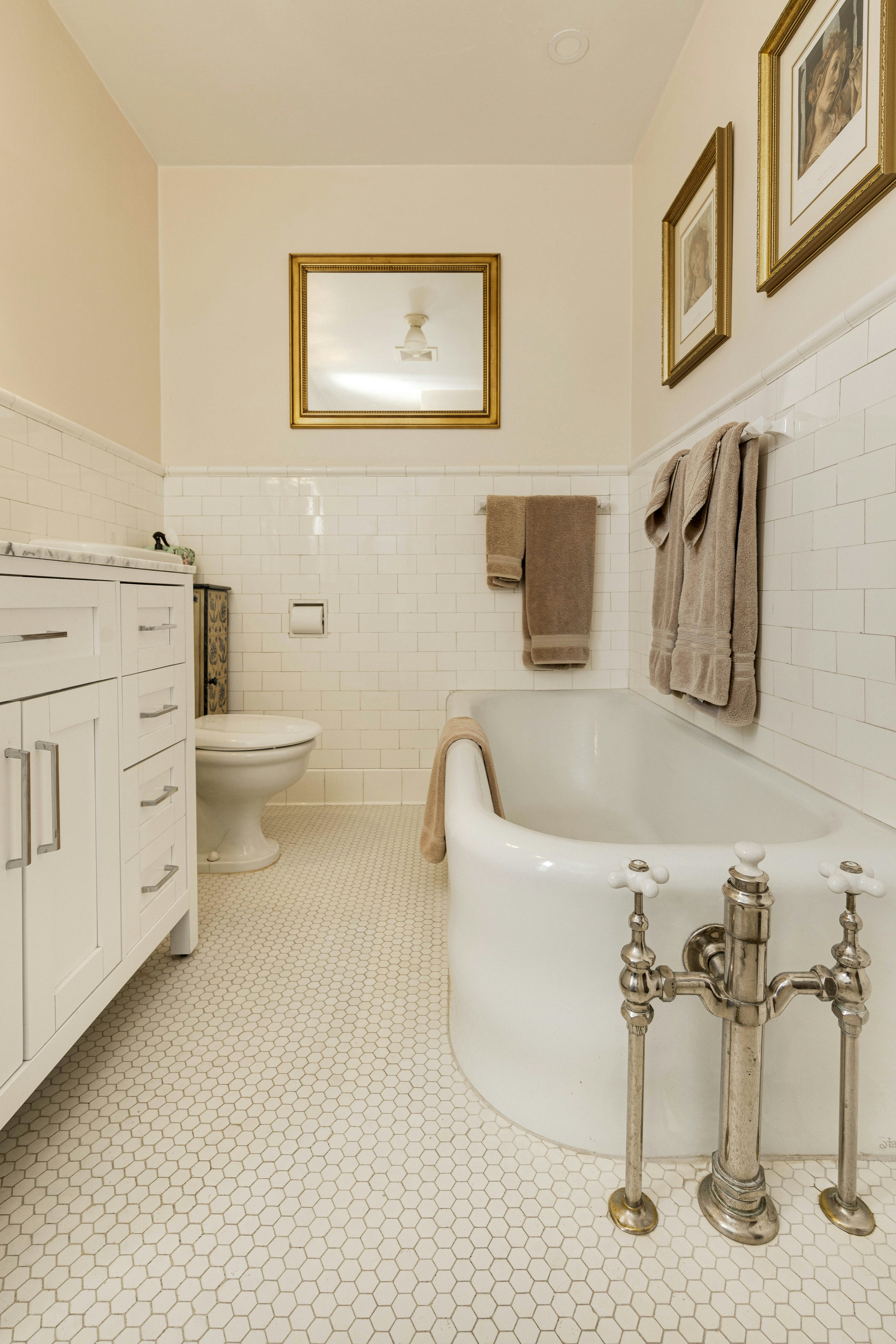 A classic clawfoot bathtub beside a vanity, with tiled walls and flooring.