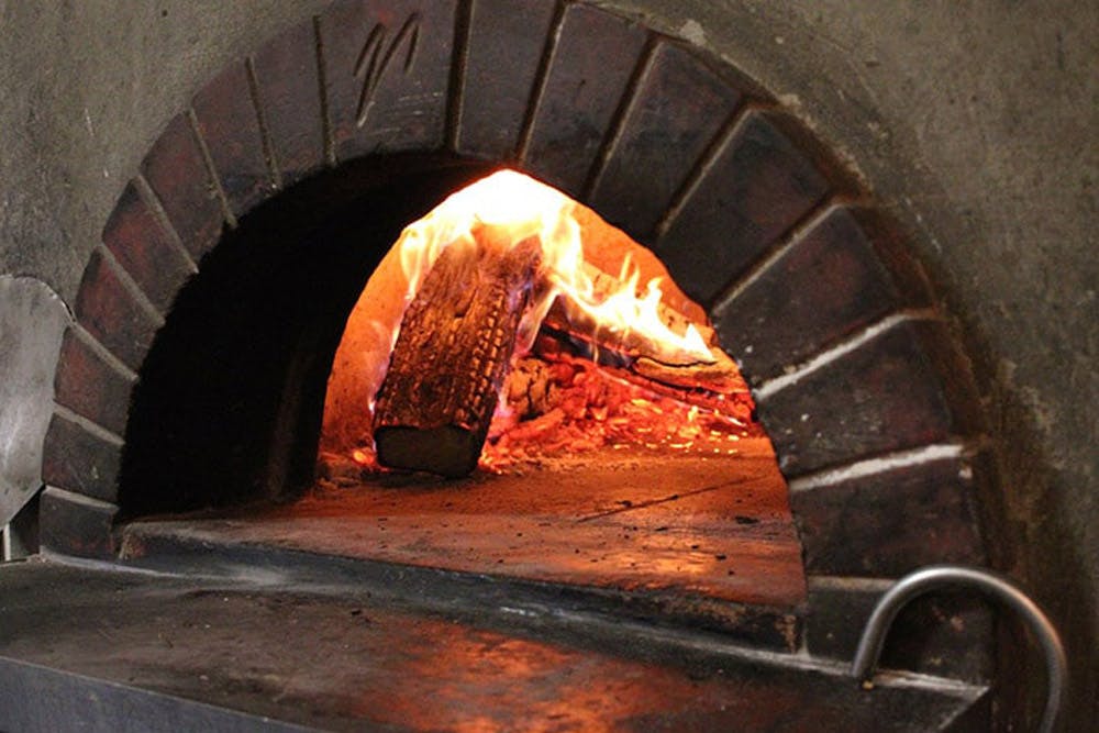 A rustic wood-fired oven with flames burning inside, ready for baking.