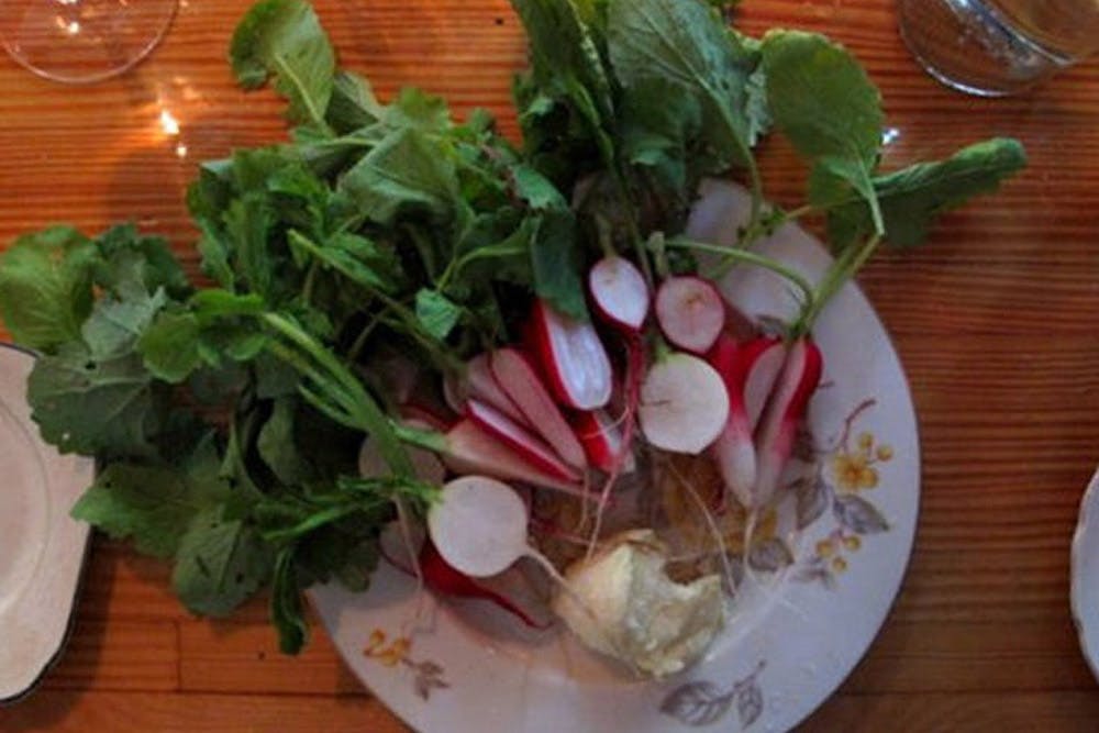 A plate of fresh radishes with leaves still attached, served with butter.