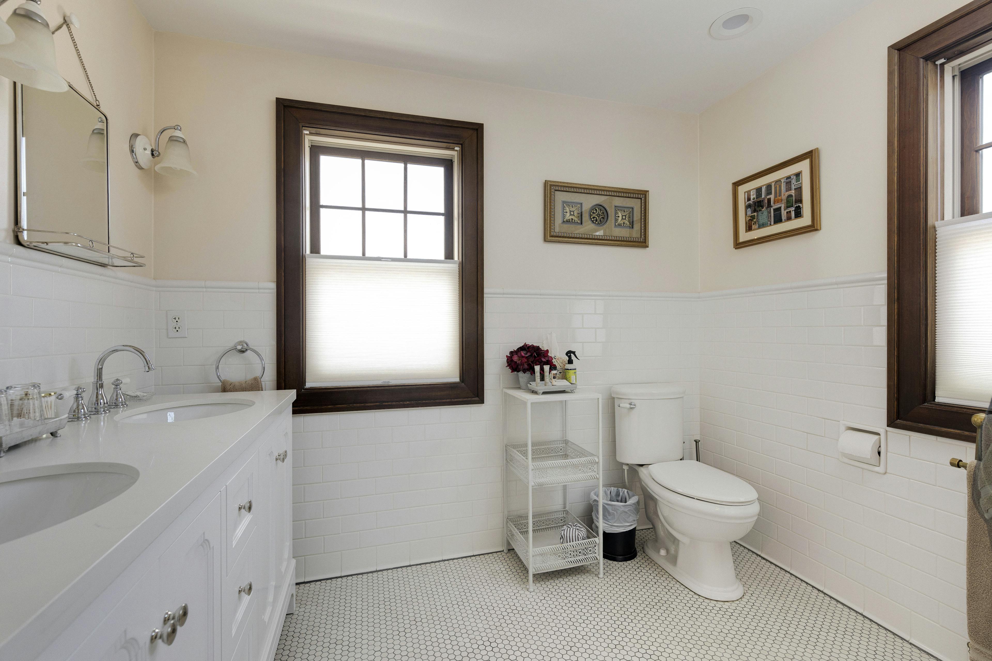 A Napoli Guest Room bathroom with a white tiled floor, vanity, and a large window.