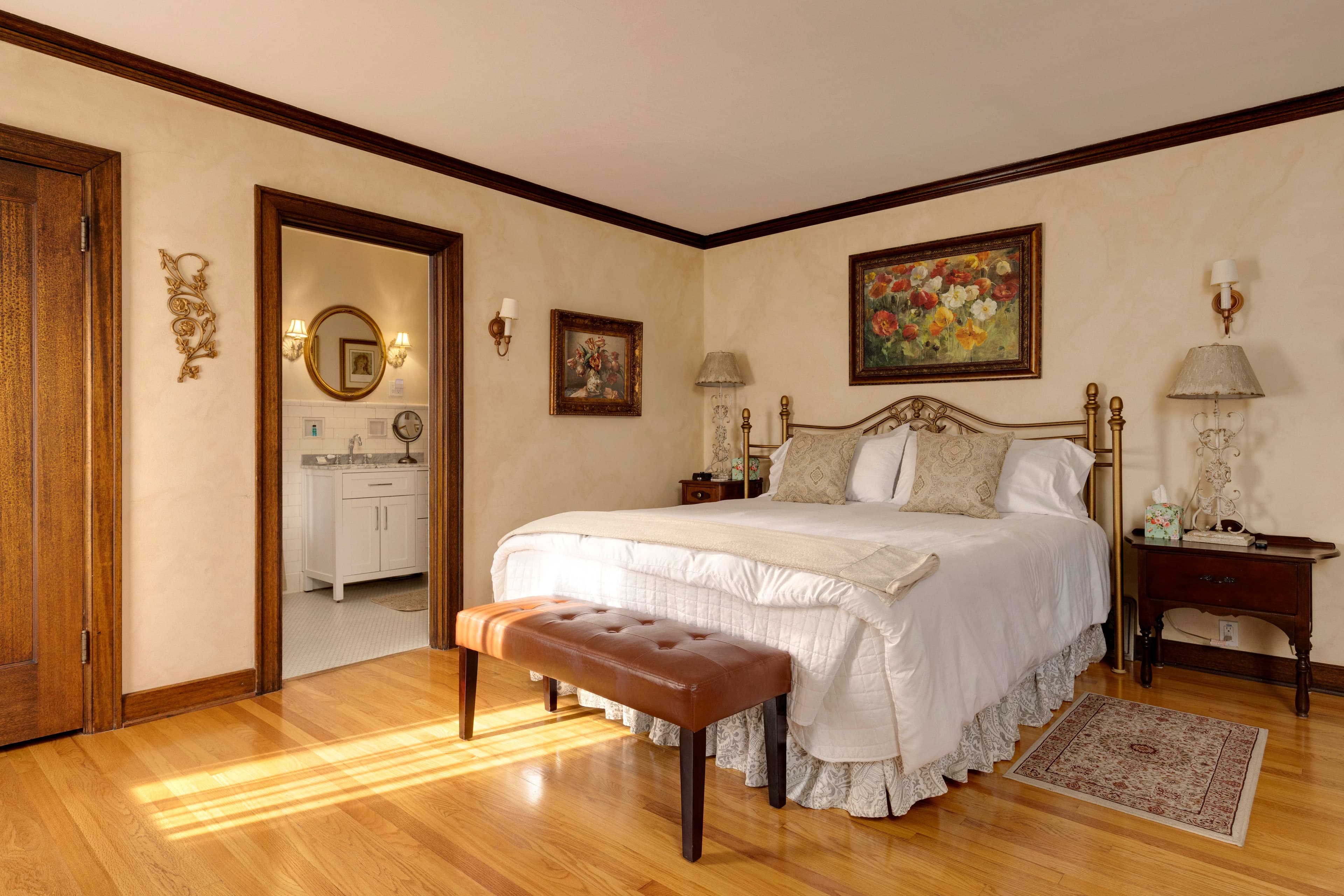 A spacious bedroom featuring a luxurious bed with an ornate headboard, side tables, and elegant décor.