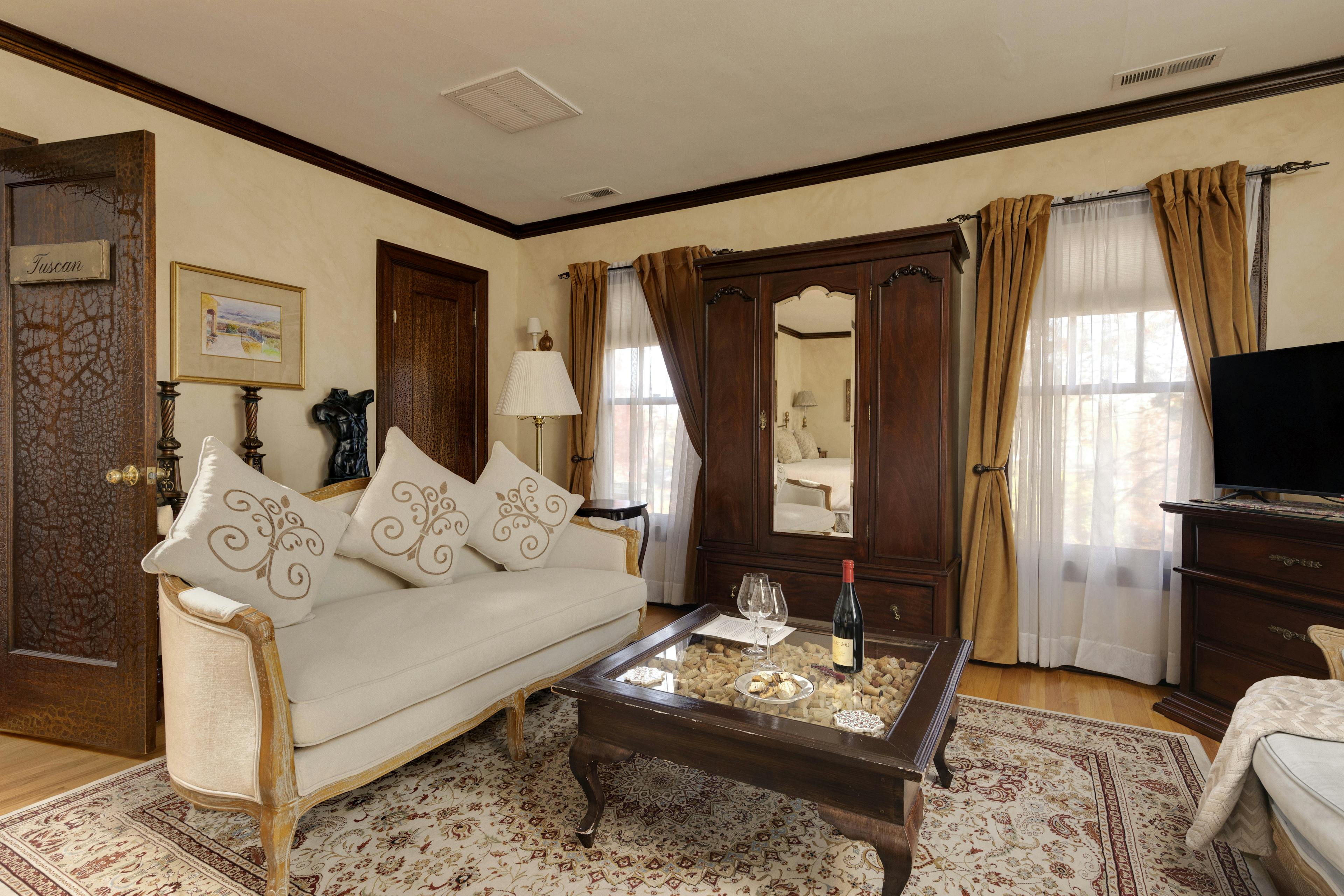 A cozy sitting area with a plush sofa, a wooden coffee table, a wardrobe, and classic decor.