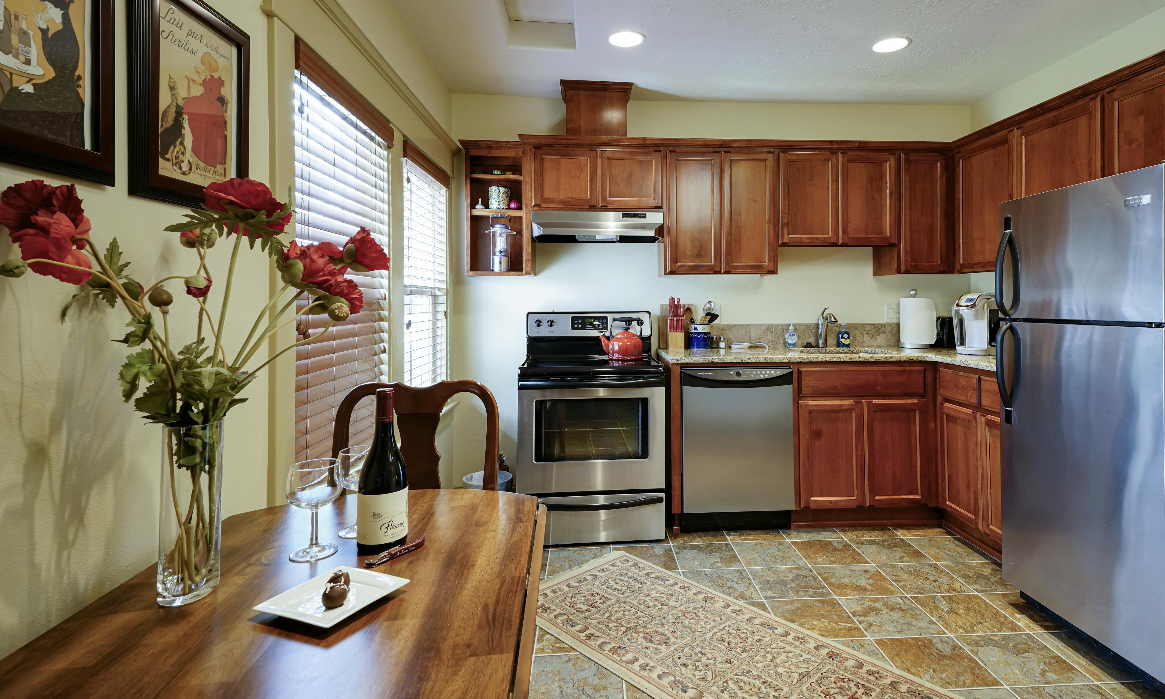 View of kitchen table, stove, counter/cabinets and refrigerator.