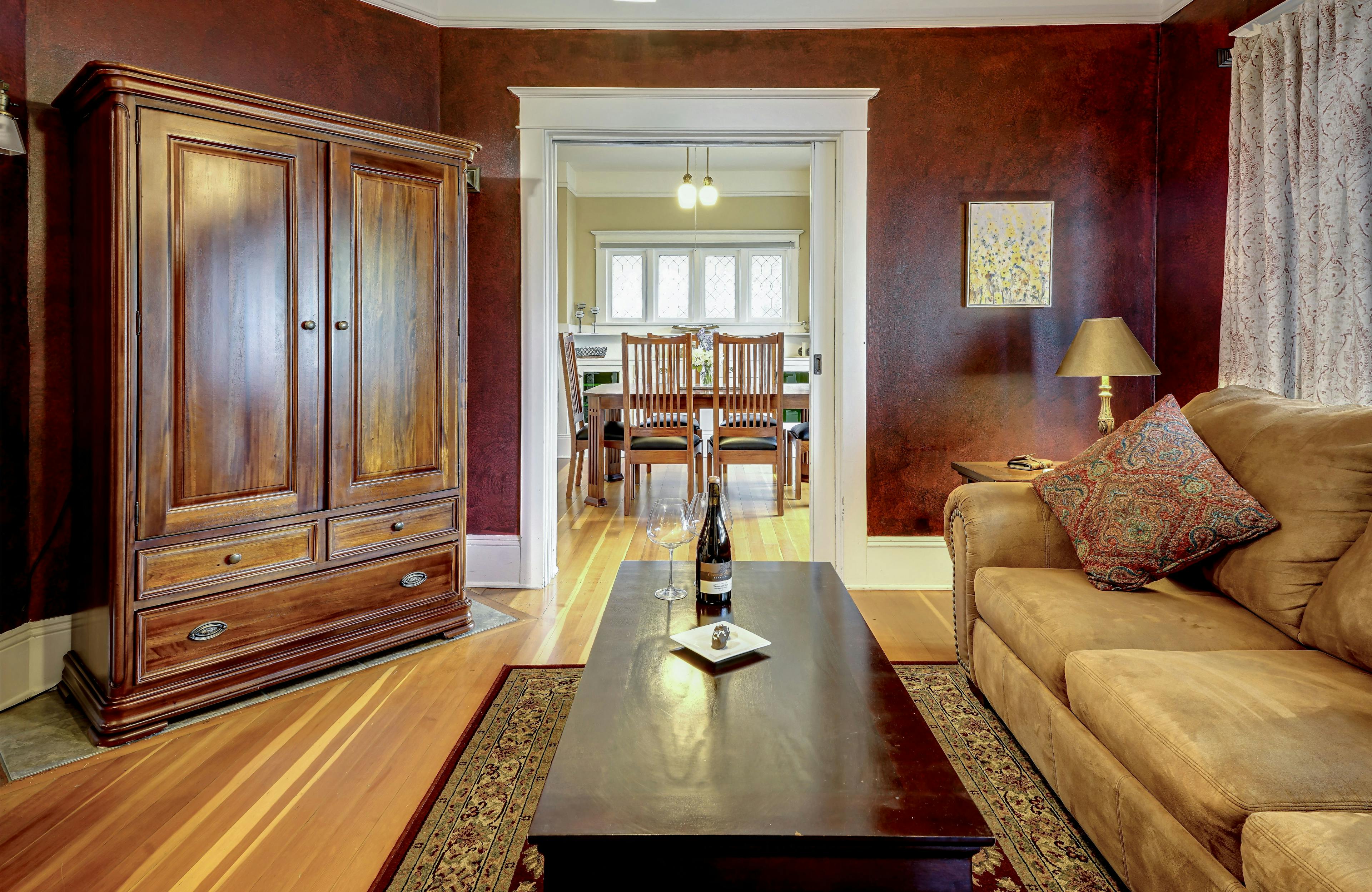 Living room with armoire housing the TV, coffee table, faux suede sofa looking into the dining room.