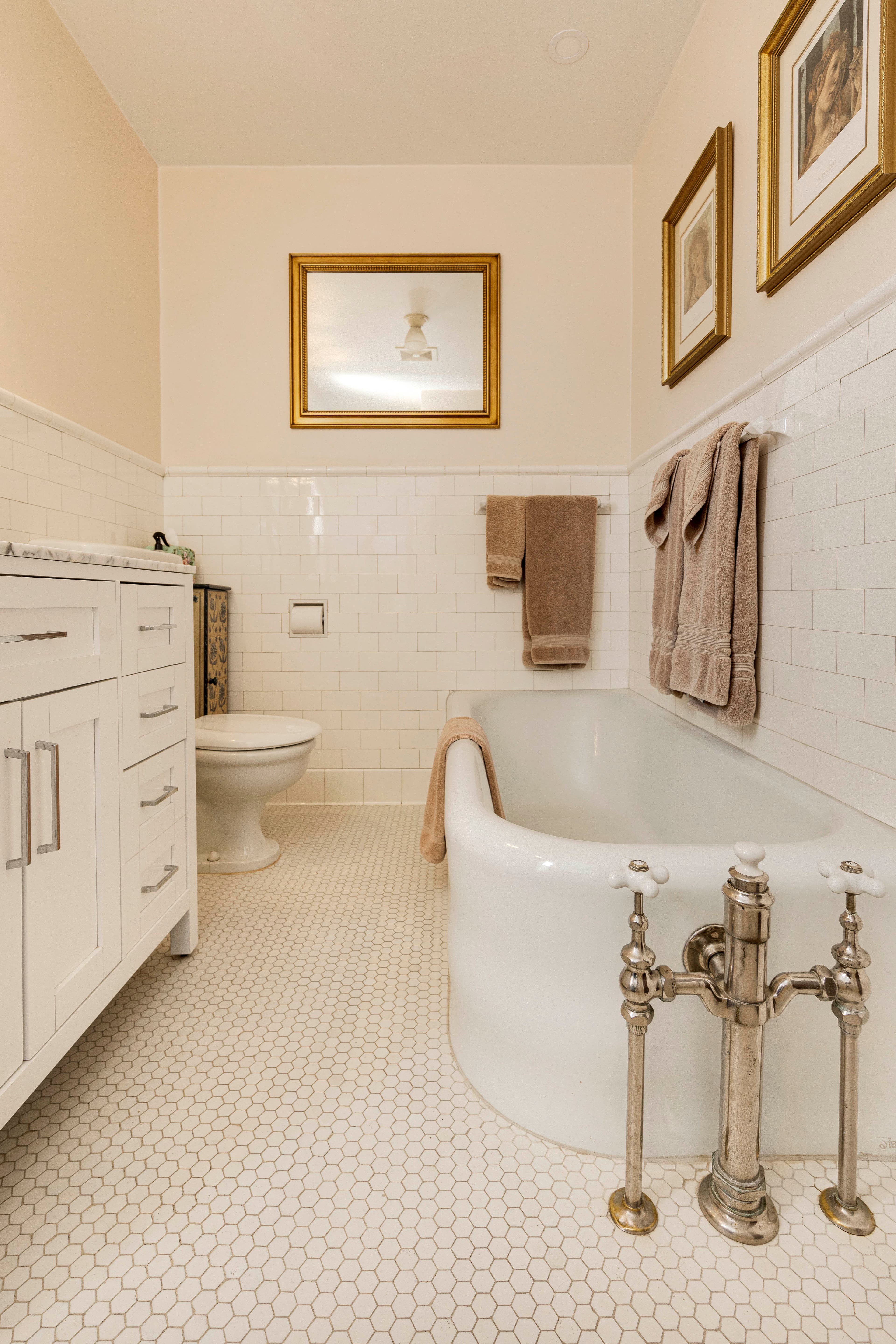 A classic clawfoot bathtub beside a vanity, with tiled walls and flooring.