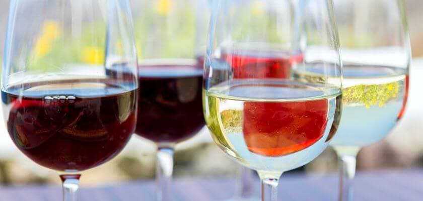 Five glasses of wine filled with different types of wine, including red and white.