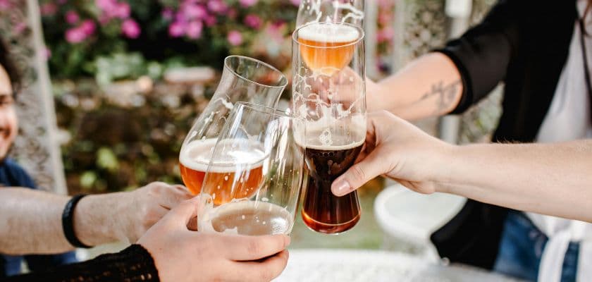 A group of people toasting with glasses of beer outdoors.