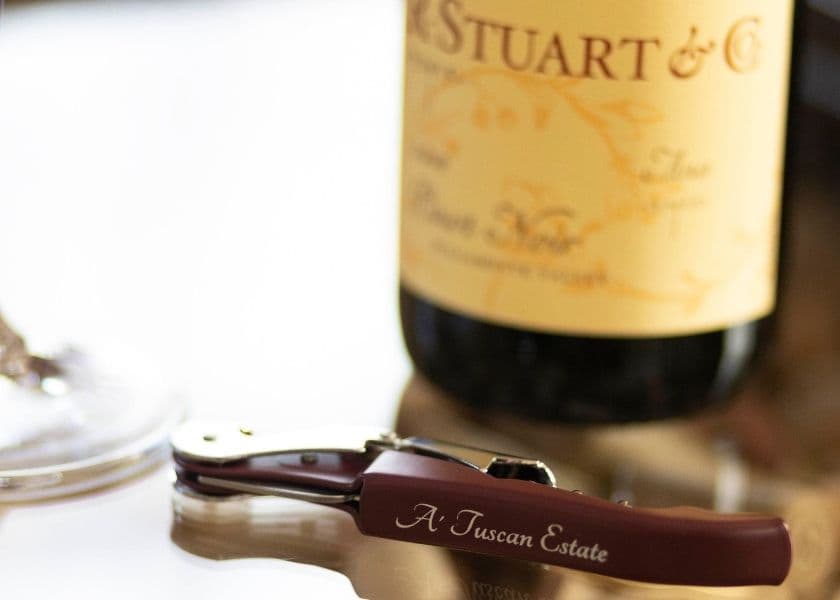 A corkscrew rests beside a bottle of Pinot Noir from A Tuscan Estate. A corkscrew rests beside a bottle of Pinot Noir from A Tuscan Estate.