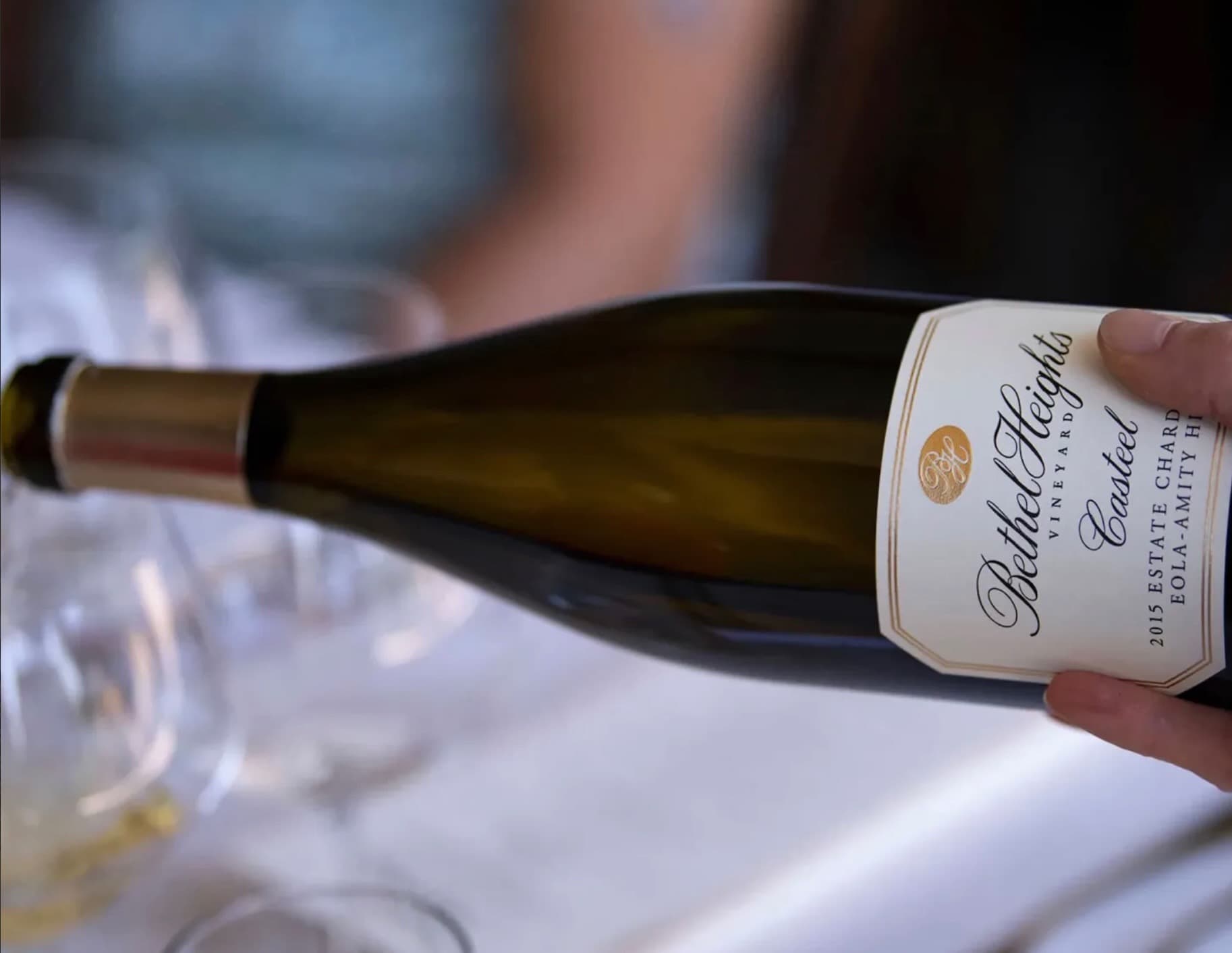 A bottle of Bethel Heights wine is being held and poured into a clear wine glass