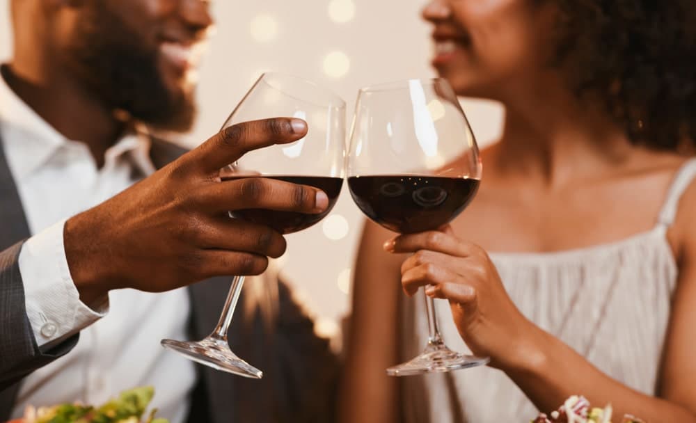 A couple clinks wine glasses together in a festive setting.