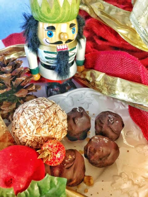 A festive nutcracker stands beside a plate of chocolate-covered treats and decorative holiday items.