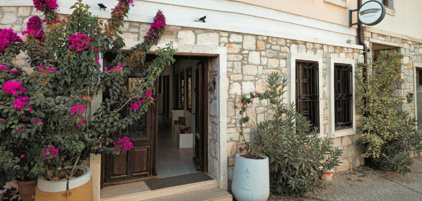 A stone building entrance adorned with vibrant pink flowers and greenery.