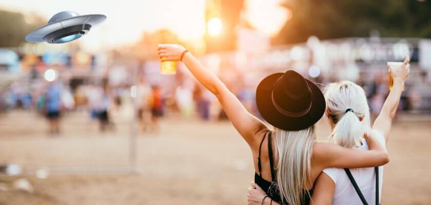 two women holding beer at a festival, ufo in corner