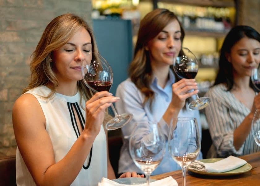 three women enjoying wine tasting with glasses of red wine